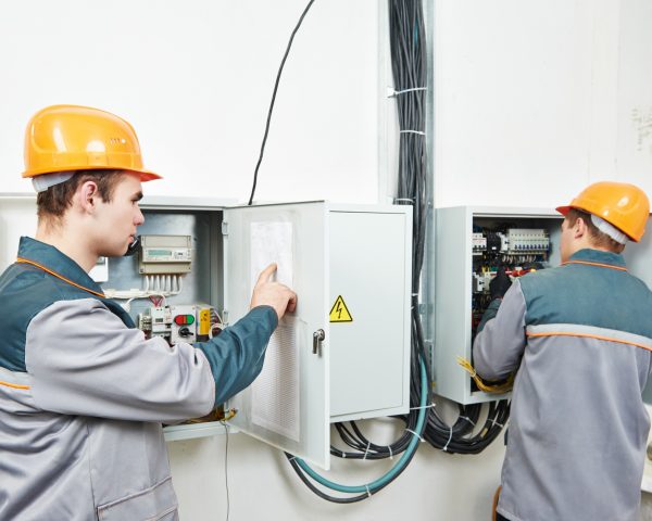two electrician builder engineer works with electric cable wiring of fuse switch box