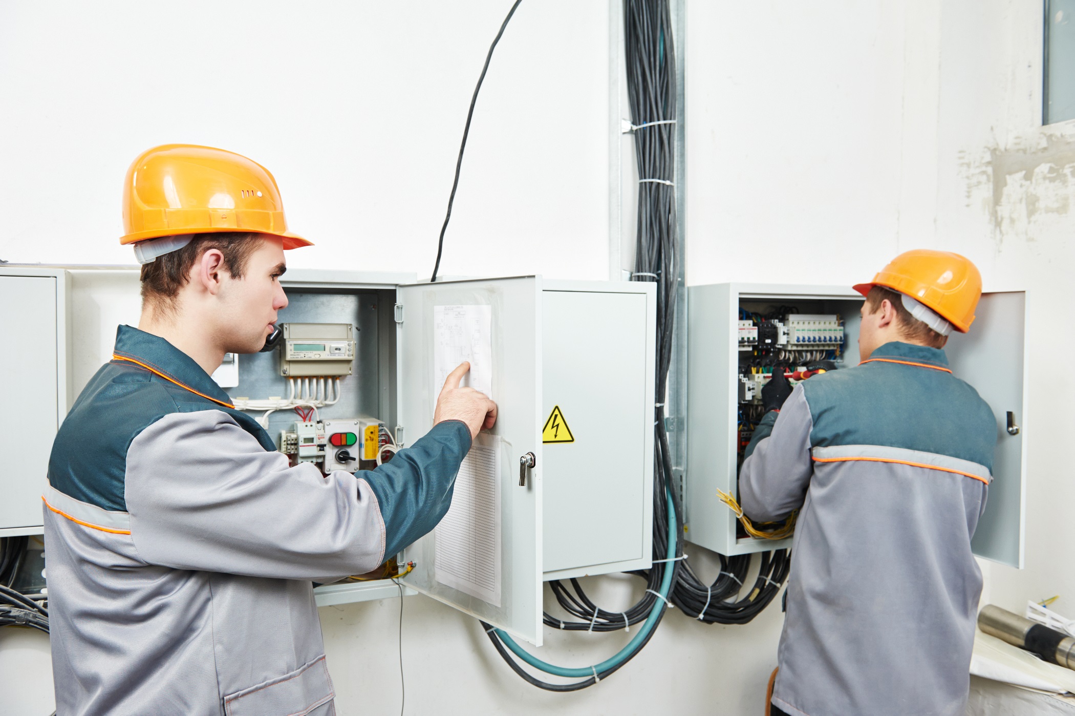 two electrician builder engineer works with electric cable wiring of fuse switch box